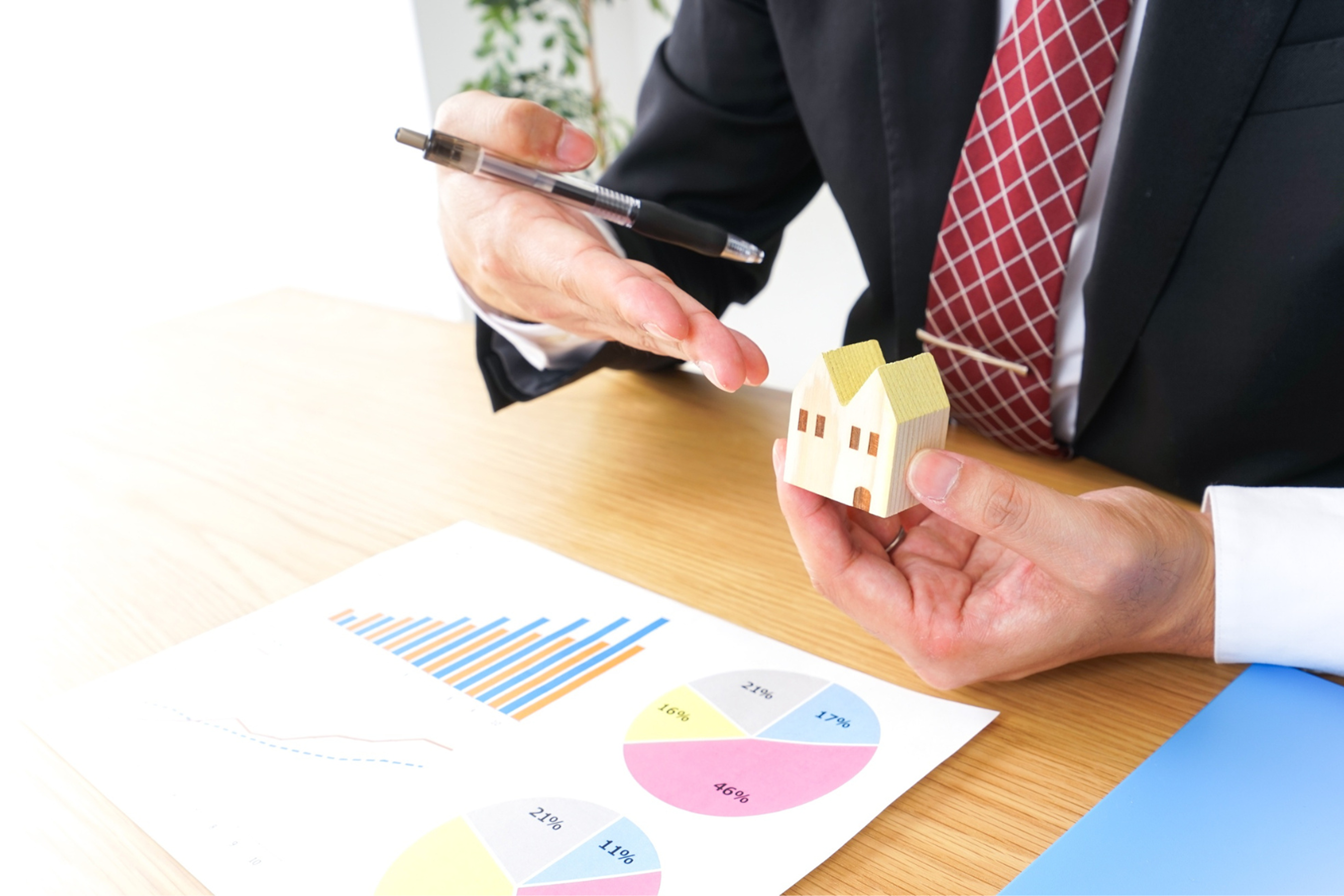 デスクで住宅の模型を手に持つビジネスパーソン